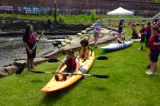 kids learning how to kayak on the ground next to a river