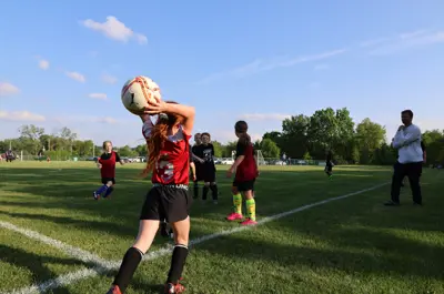 Young girl throwing a soccer ball overhead