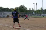 person standing on first base while another player pitches a softball
