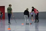 young girl being shown where to hit a field hockey ball