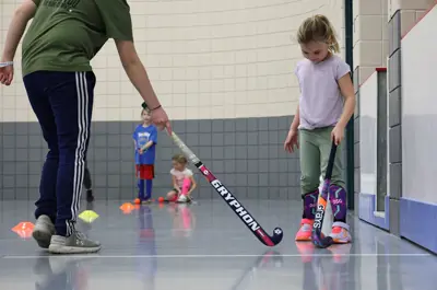 young girl and mentor holding field hockey sticks