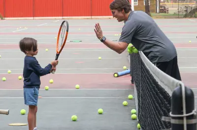 coach and kid about to high-five with a tennis racket